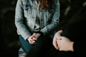 Two people sitting near each other with hands clasped on their lap